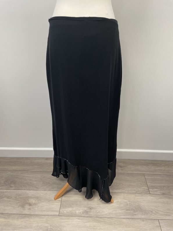 Aide black skirt with side zip. It has a chiffon and beaded assymetric hem